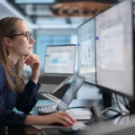 Analyst reviewing data across multiple screens.