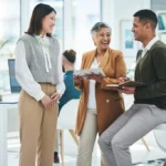 Three colleagues discussing work in a modern office.