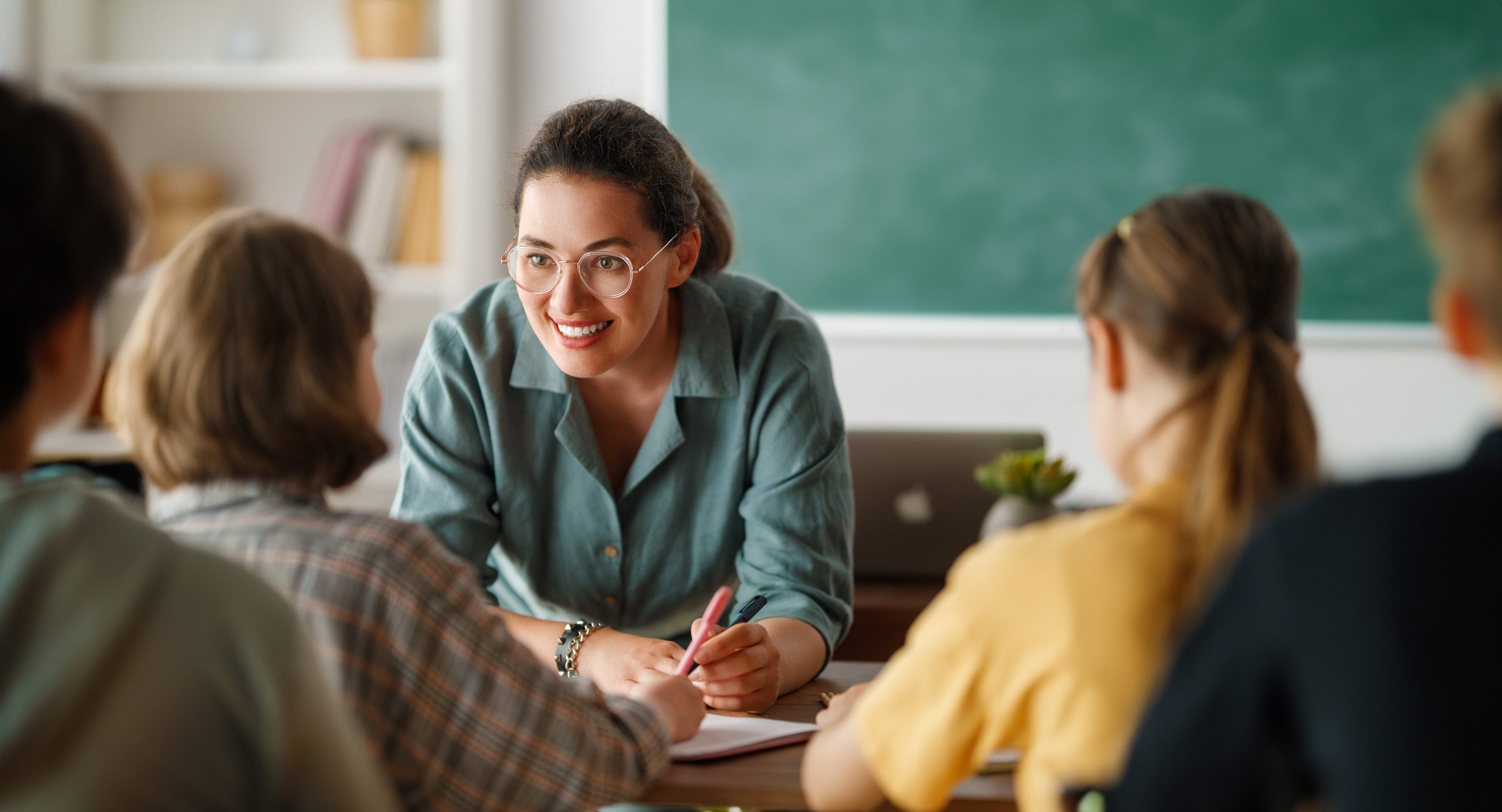 teacher helping a classroom full of young students