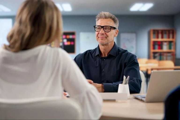 Professional meeting with a man wearing glasses discussing ideas with a colleague in an office.