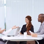 Team meeting with diverse colleagues discussing ideas around a conference table.