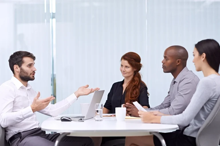 Team meeting with diverse colleagues discussing ideas around a conference table.